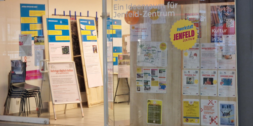 Die gläserne Front eines Ladenlokals in dem viele Plakate und Info-Stellwände zu sehen sind